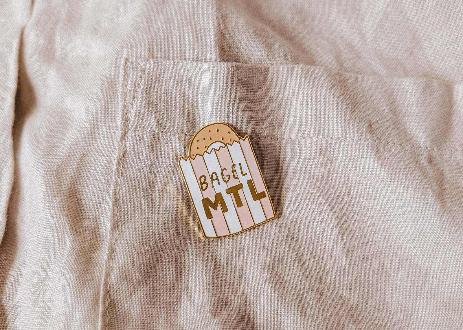 mimi-and-august Pin with 'Bagel MTL' on a beige shirt