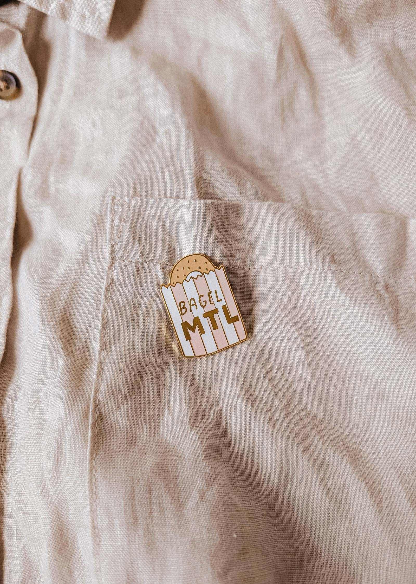 mimi-and-august Pin with 'Bagel MTL' on a beige shirt