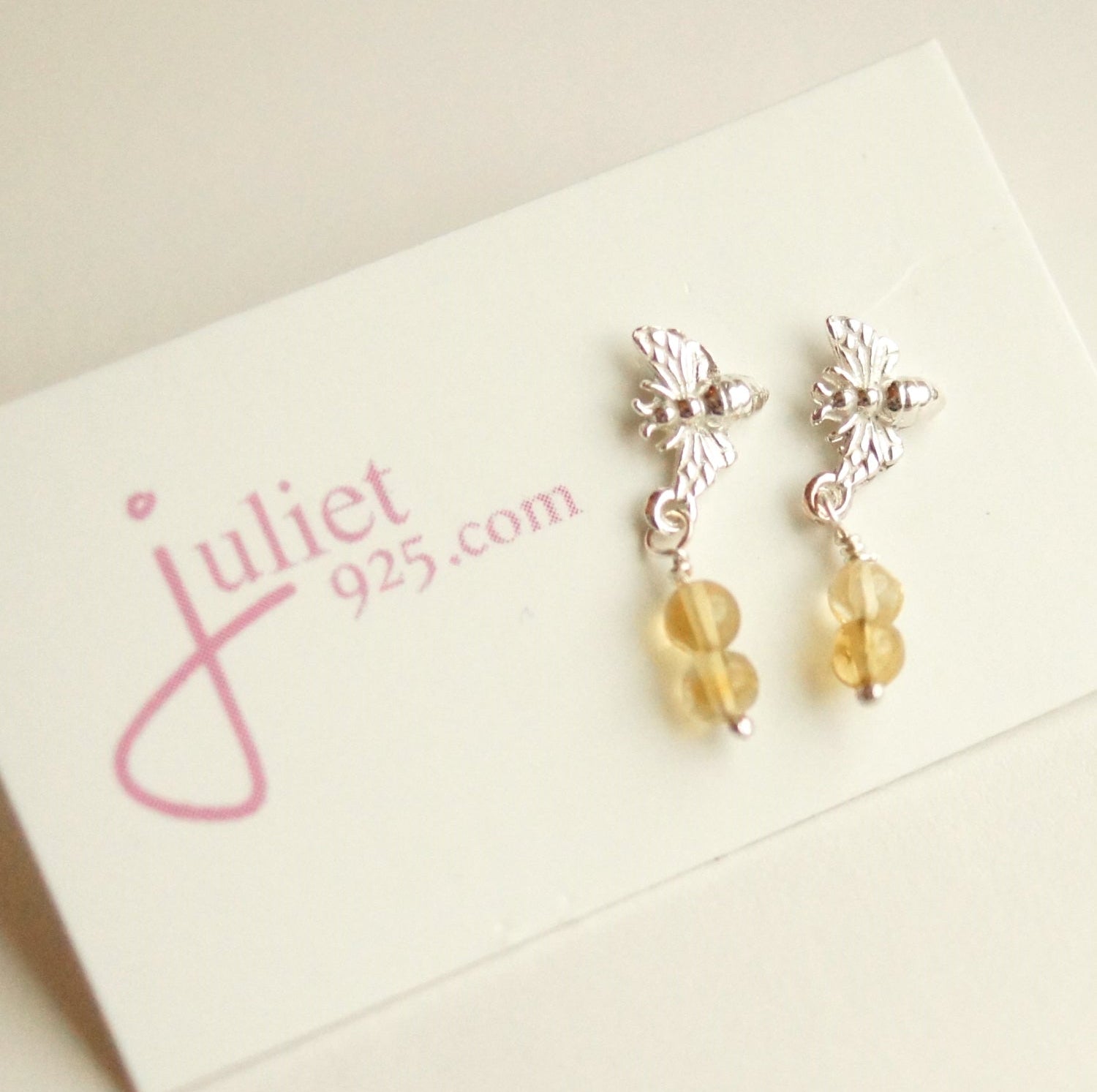 Silver earrings with yellow beads on a 'juliet 925' branded card.