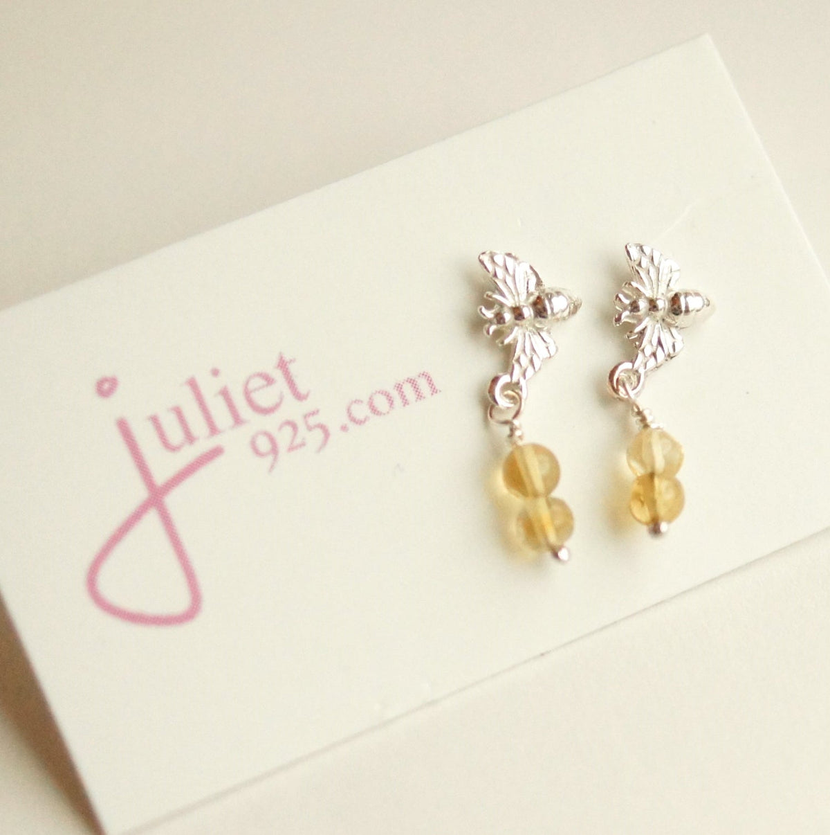 Silver earrings with yellow beads on a 'juliet 925' branded card.