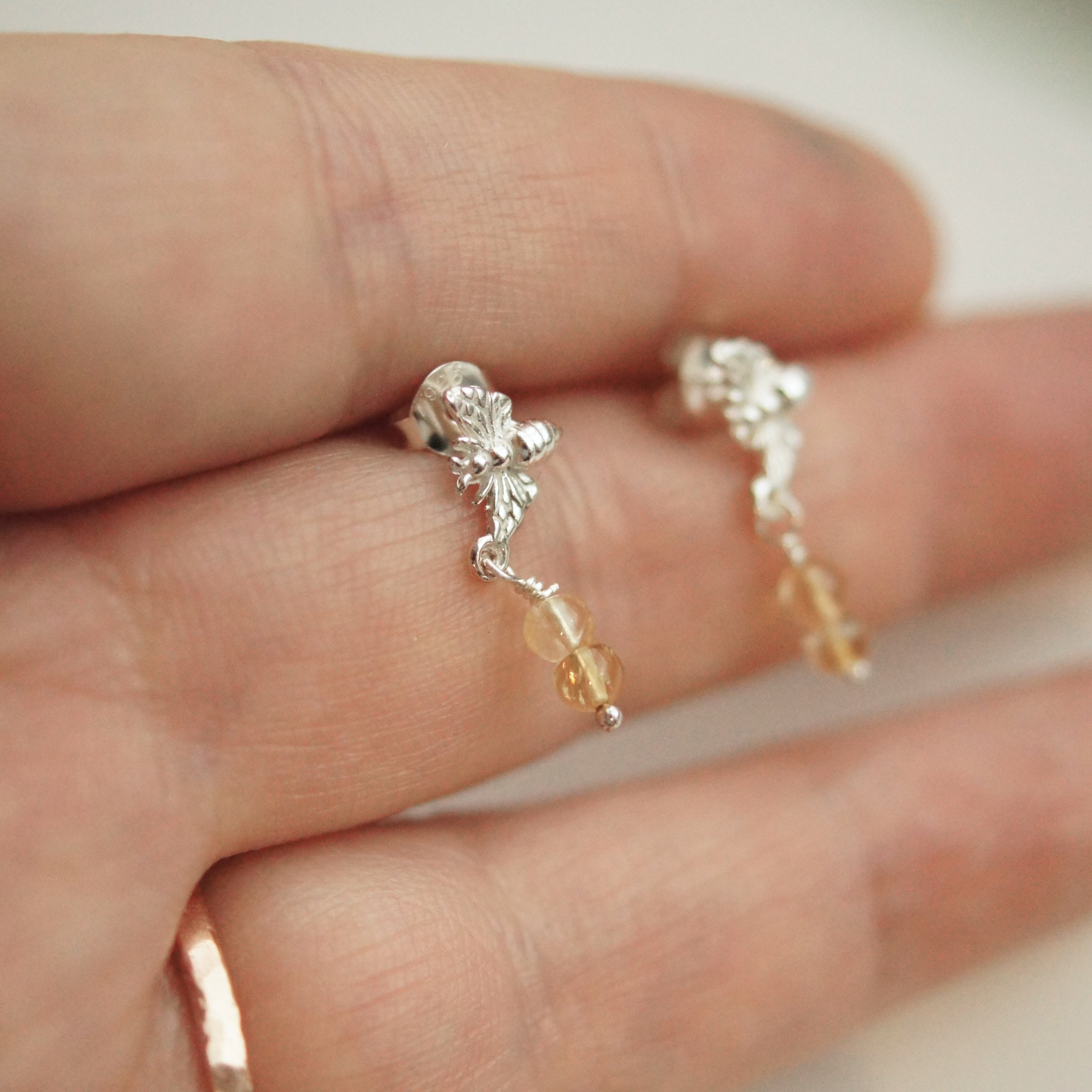 Silver earrings with small beads on a hand