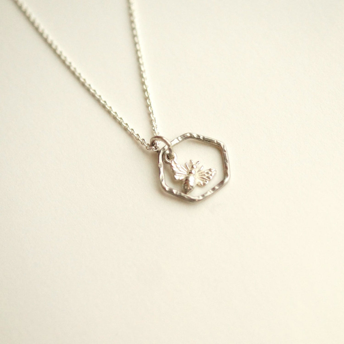 Silver necklace with a heart-shaped pendant on a light beige background