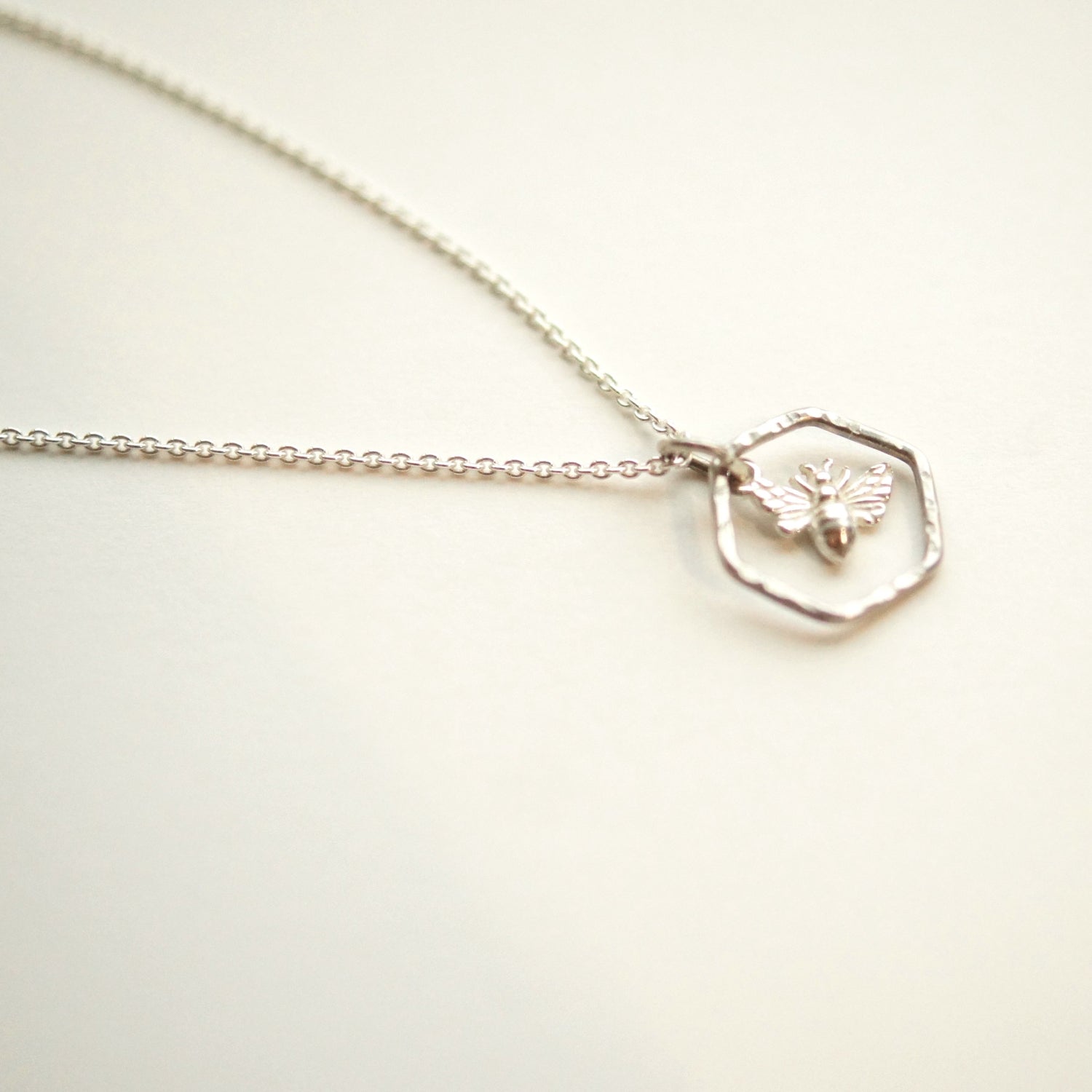 Silver necklace with a hexagonal pendant on a light background