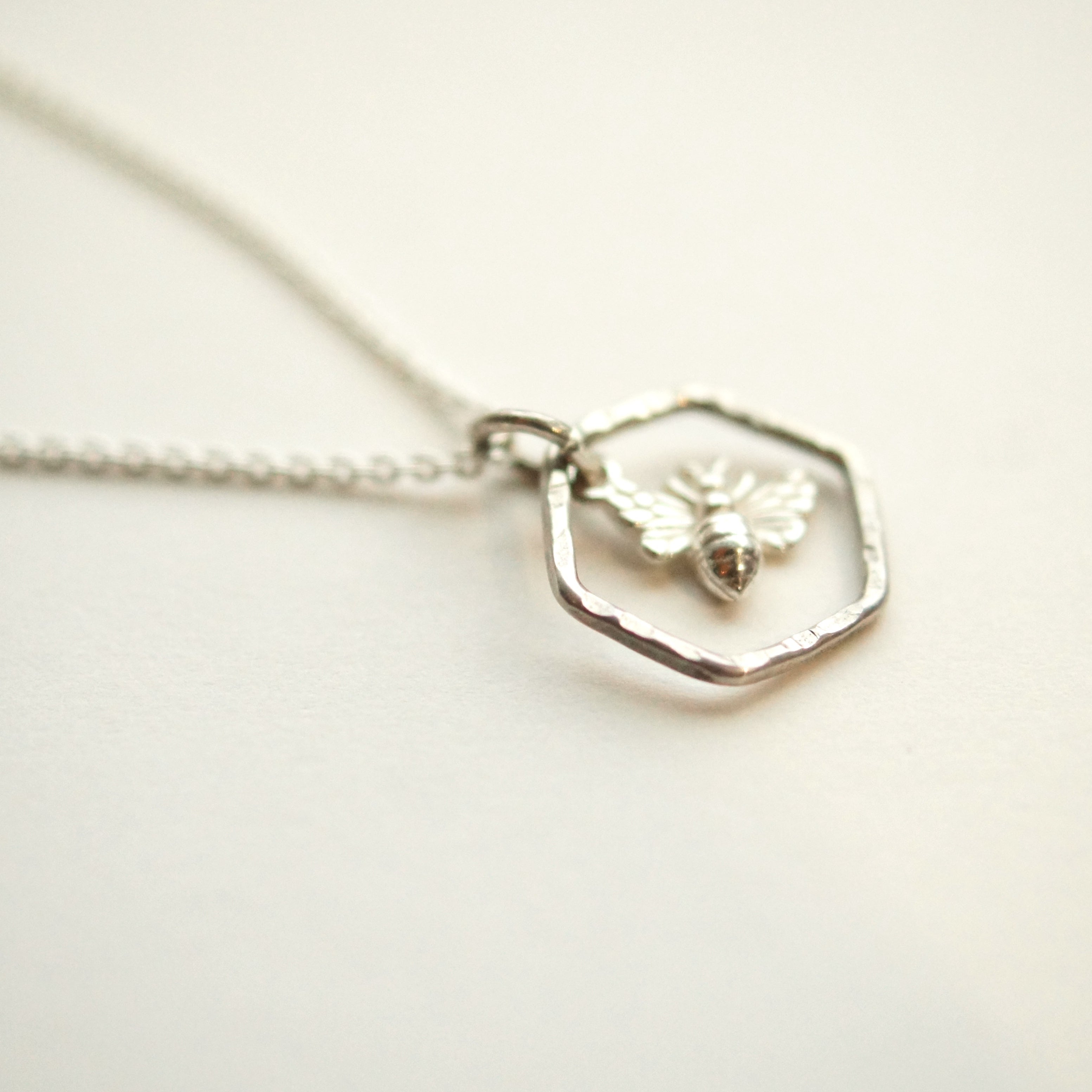 Silver necklace with a hexagonal pendant on a light background