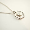 Silver necklace with a hexagonal pendant on a light background