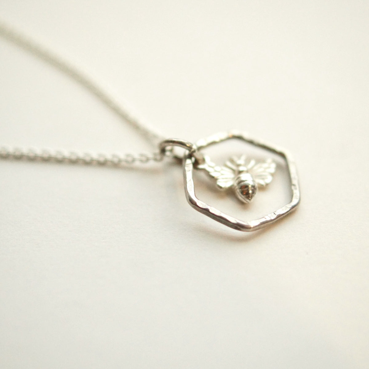 Silver necklace with a hexagonal pendant on a light background