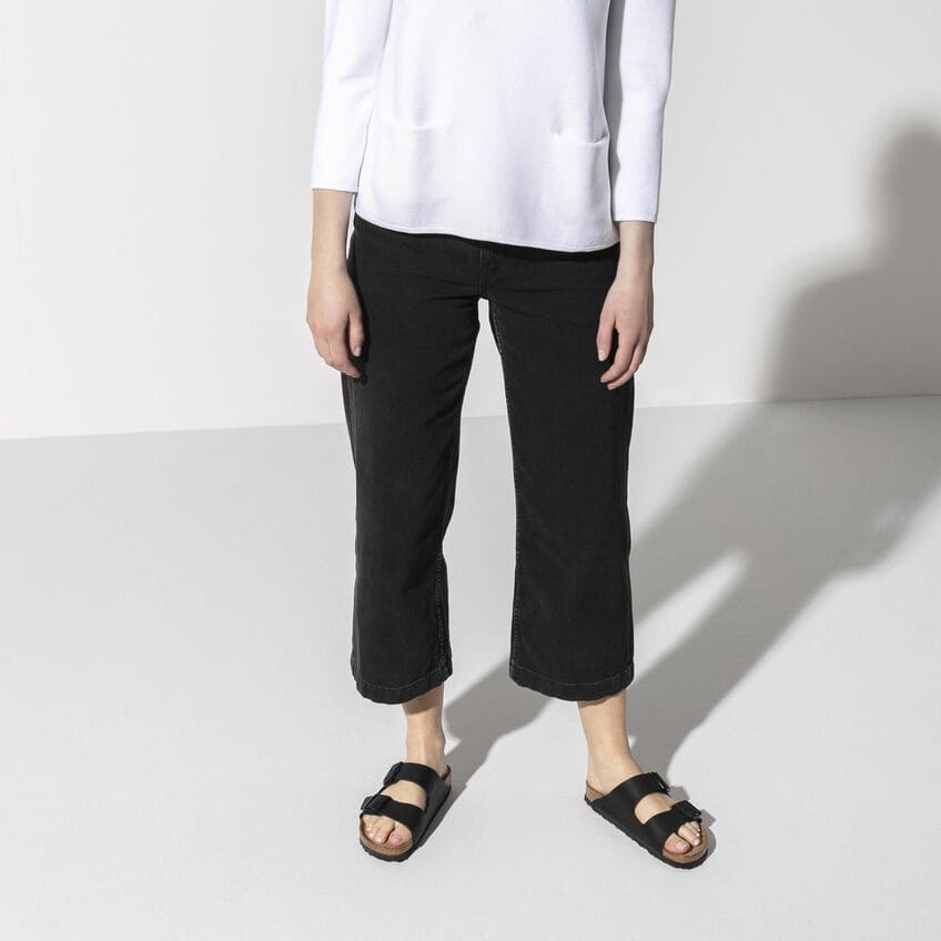 Woman wearing black cropped jeans and Birkenstock Arizona Soft Footbed sandals in black.