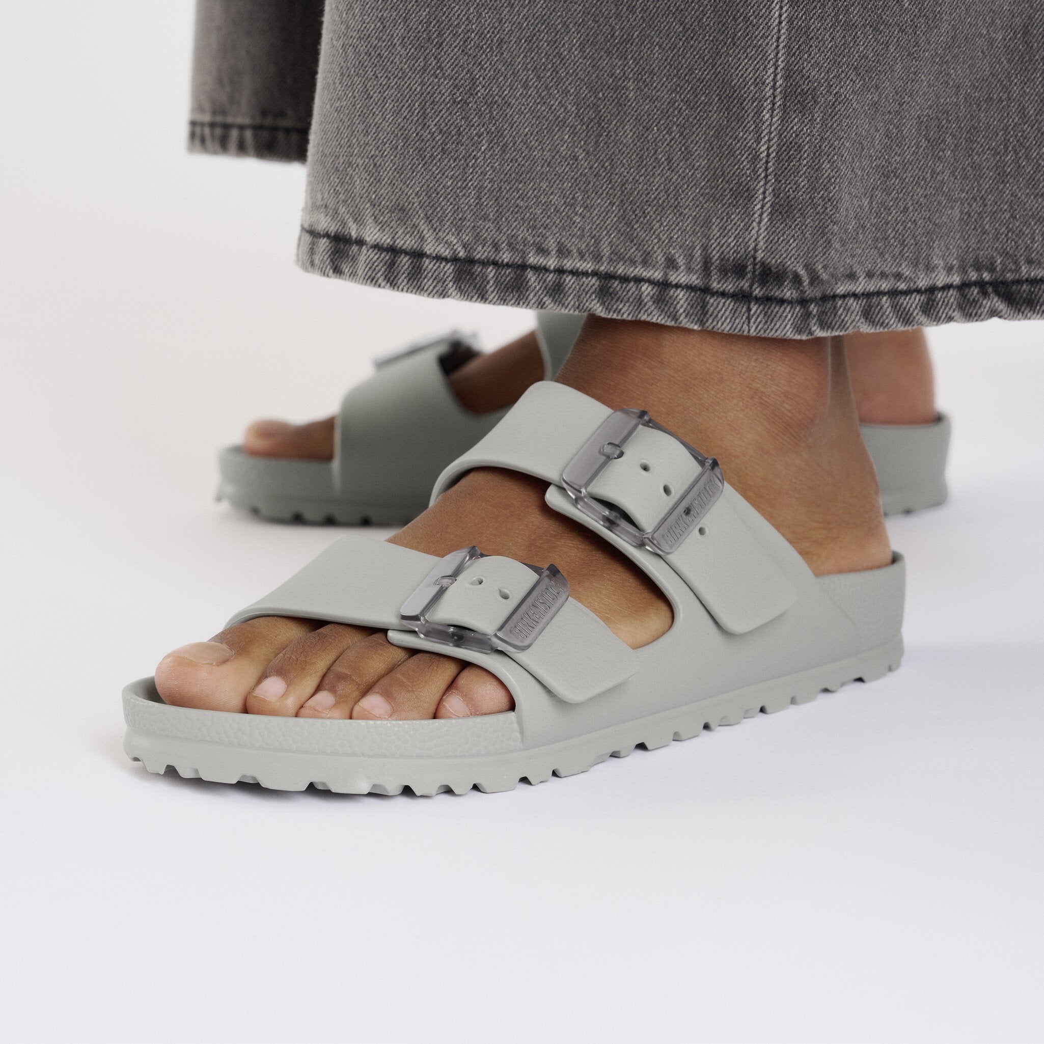 Birkenstock Arizona Stealth Buckle Stone Coin sandals on feet, showcasing lightweight, water-friendly design and translucent buckles.