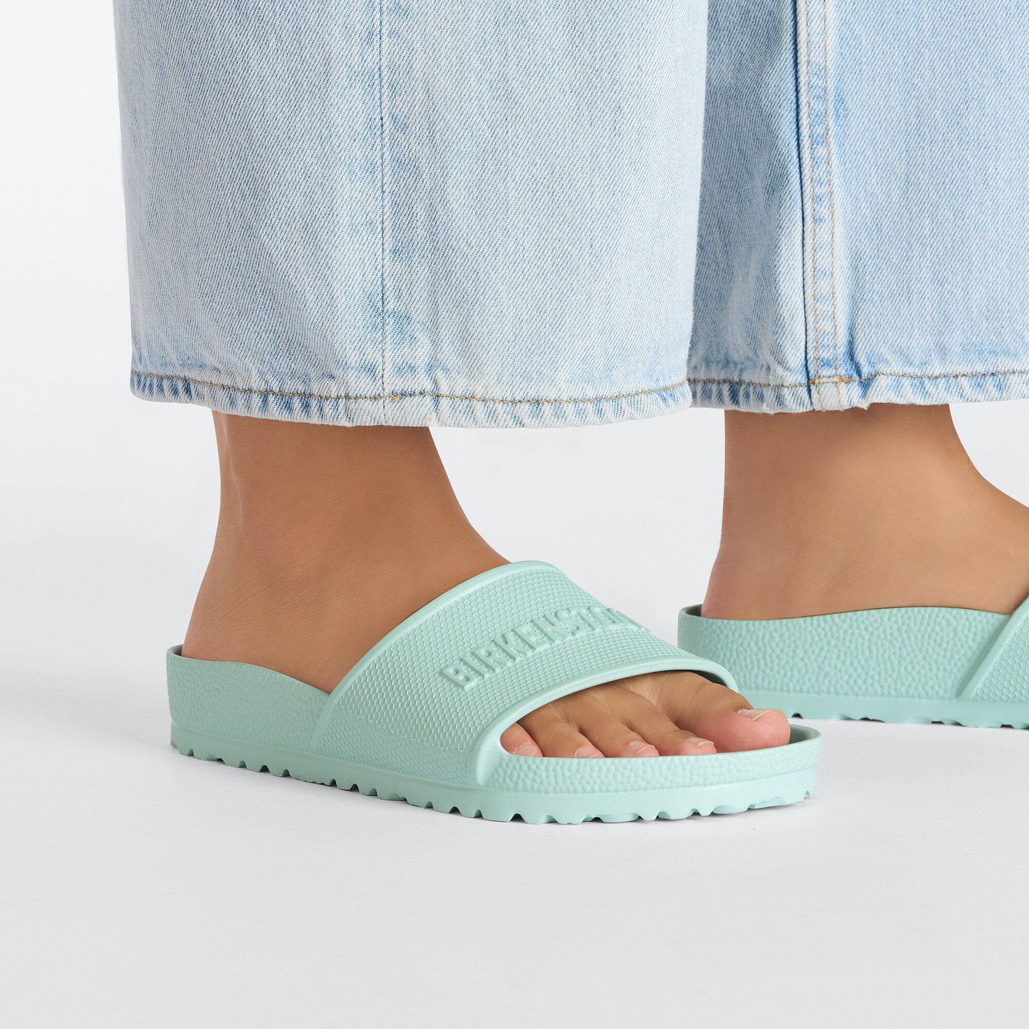 Birkenstock Barbados EVA Surf Green slide sandals displayed on feet with casual denim outfit.