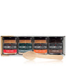 Four jars of Caramels & Faas with a wooden spoon on a white background