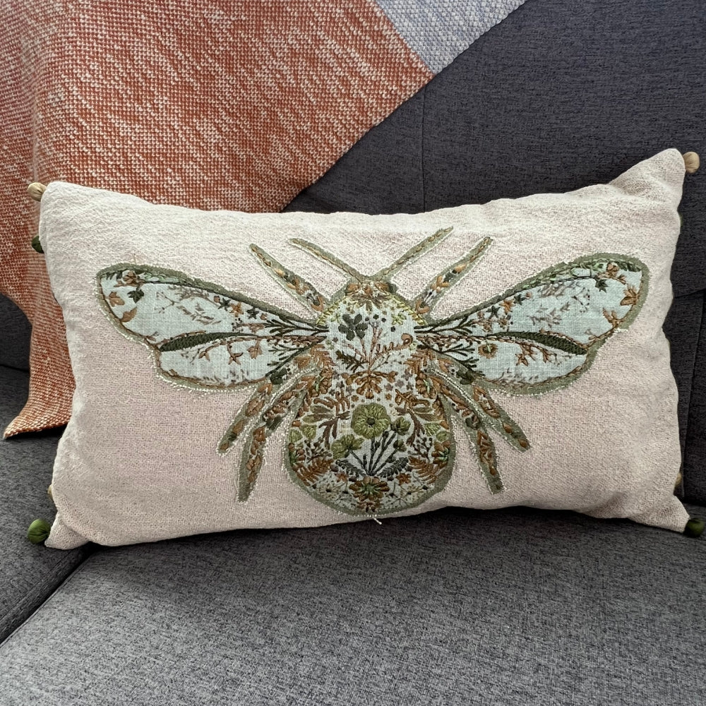 Decorative pillow with a bee design on a gray surface
