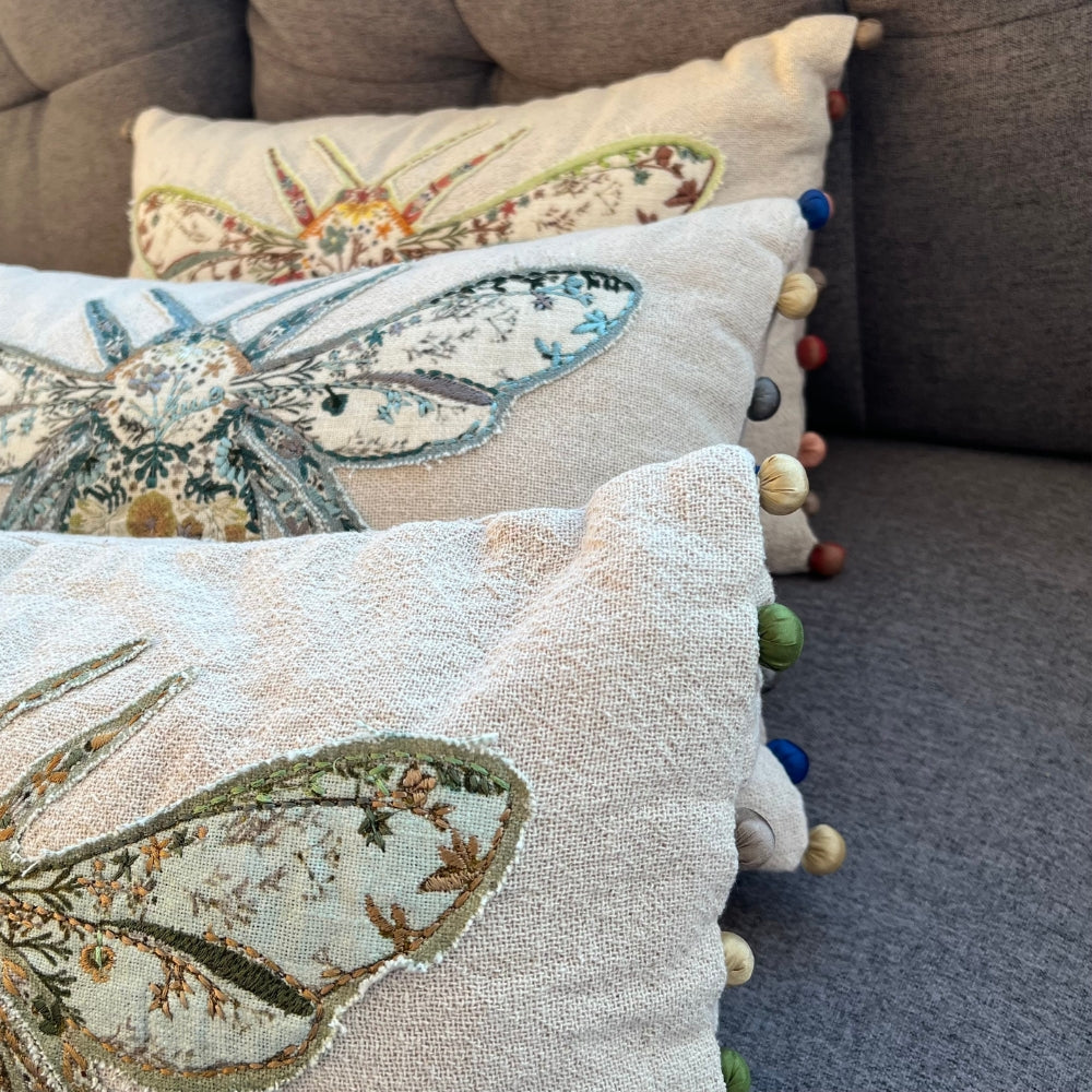 Decorative pillows with embroidered designs on a sofa