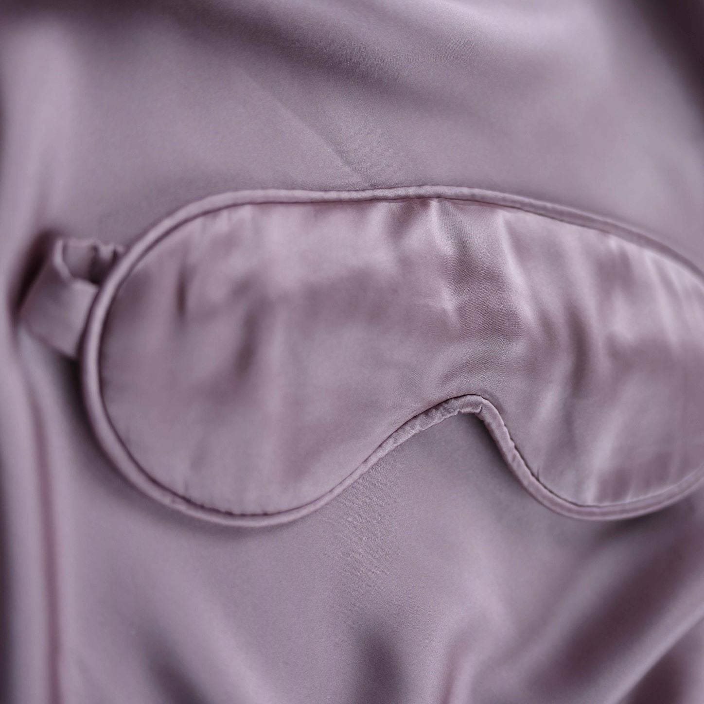 Pink satin eye mask on a matching fabric background