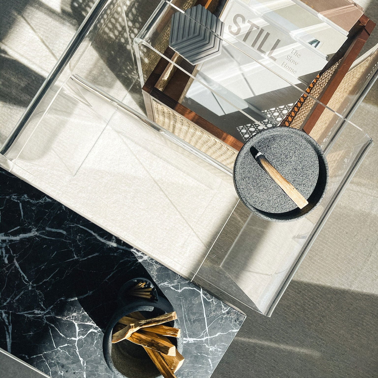 Glass coffee table with decorative items including a glass box labeled 'STILL' and a small round mirror.