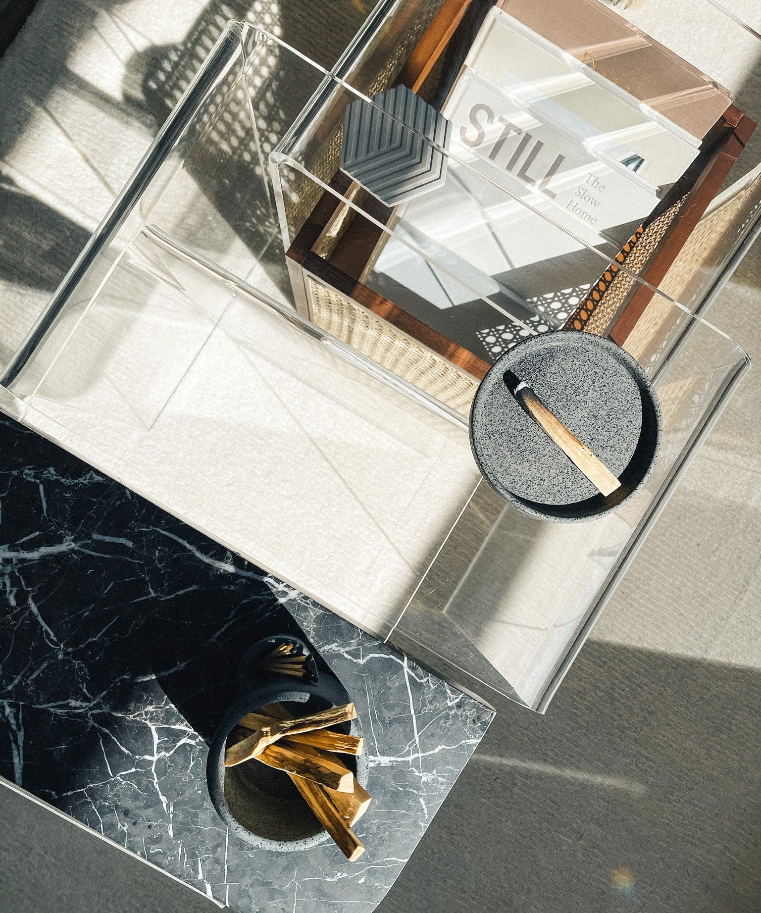 Glass coffee table with decorative items including a glass box labeled 'STILL' and a small round mirror.