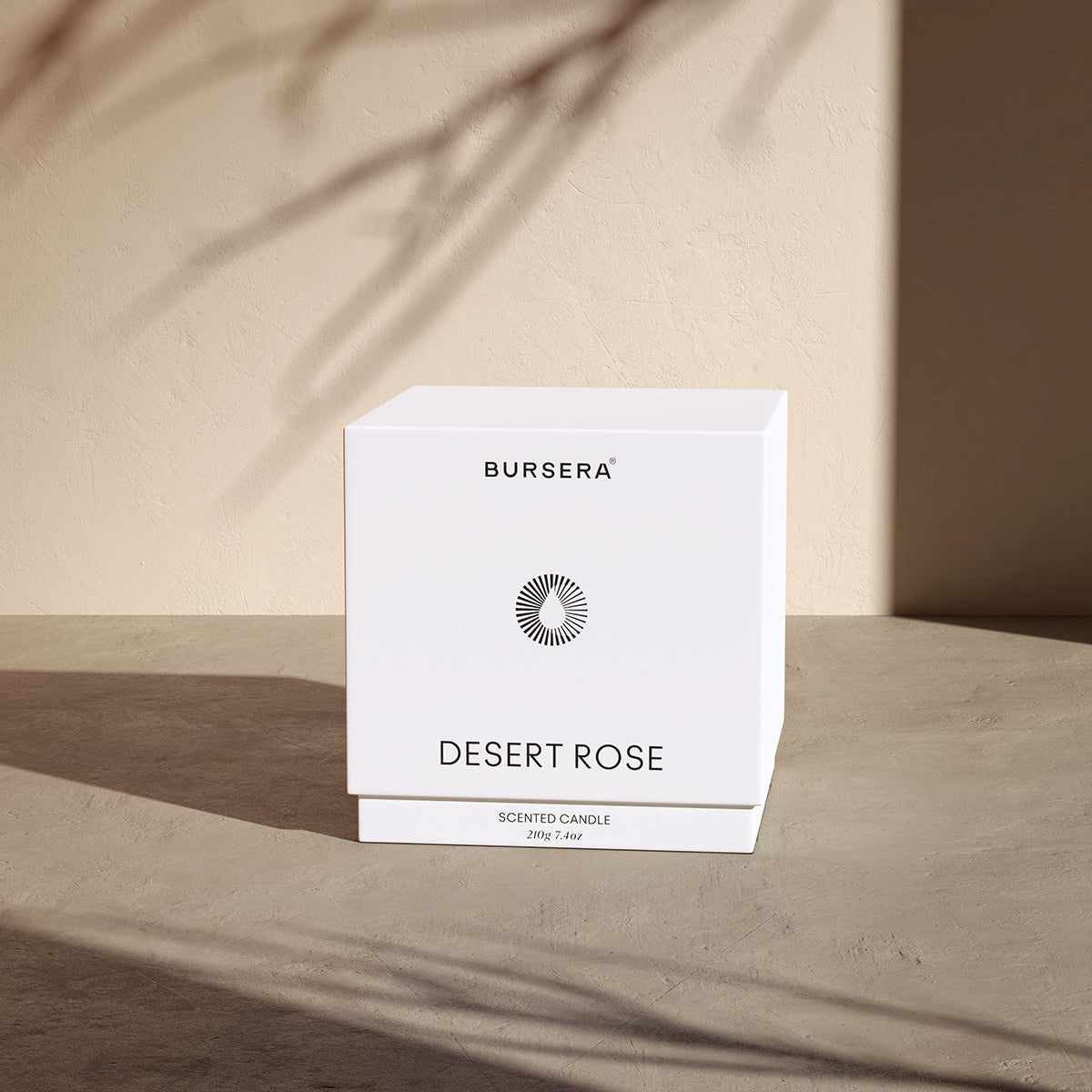 Bursera Desert Rose scented candle packaging on a wooden surface with a neutral background