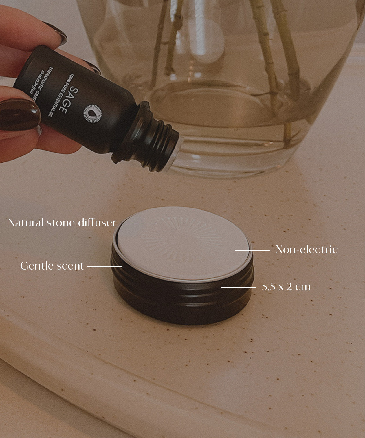 Hand holding a diffuser bottle with product details on a stone surface