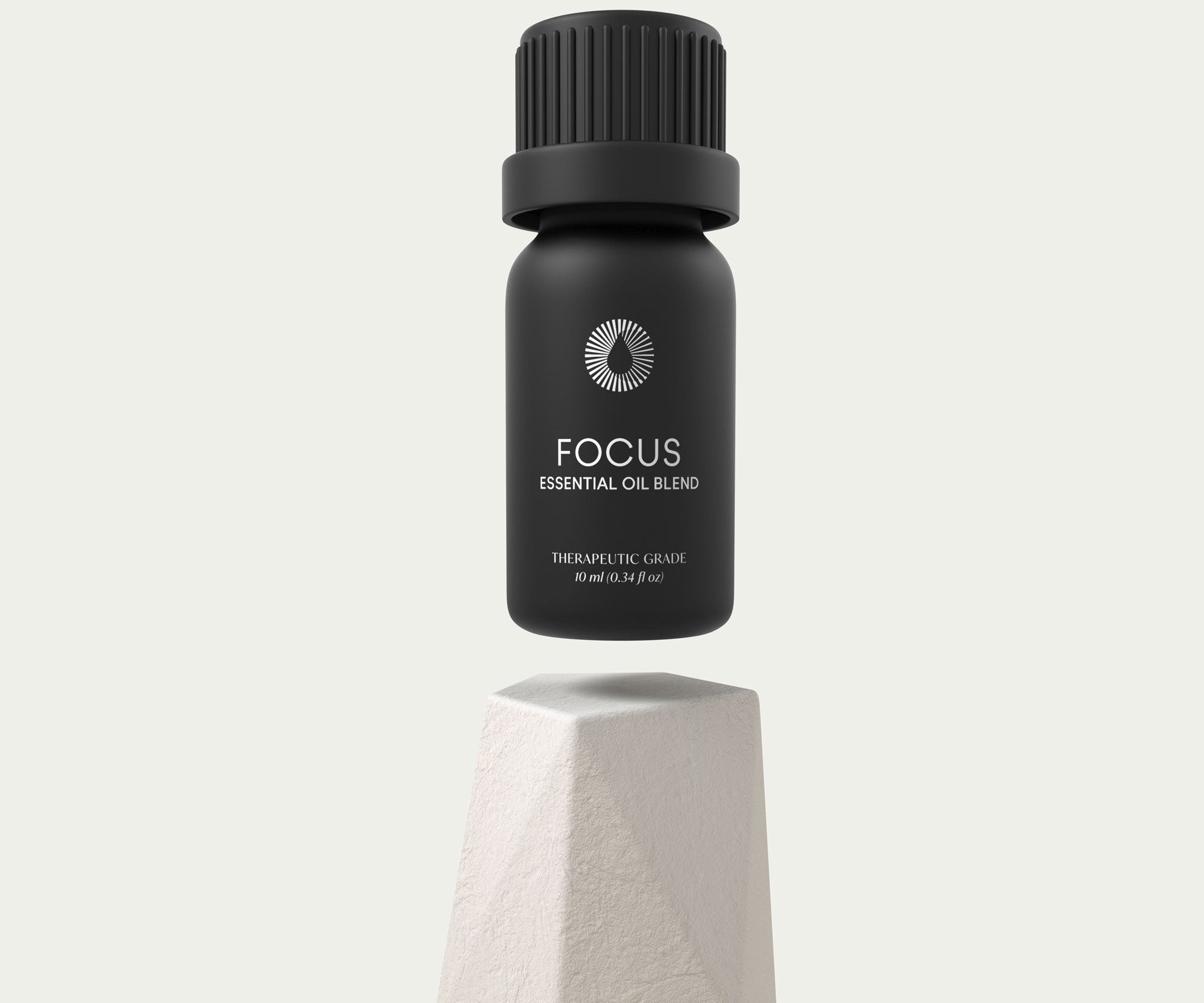 Black essential oil bottle labeled 'Focus' on a light gray background