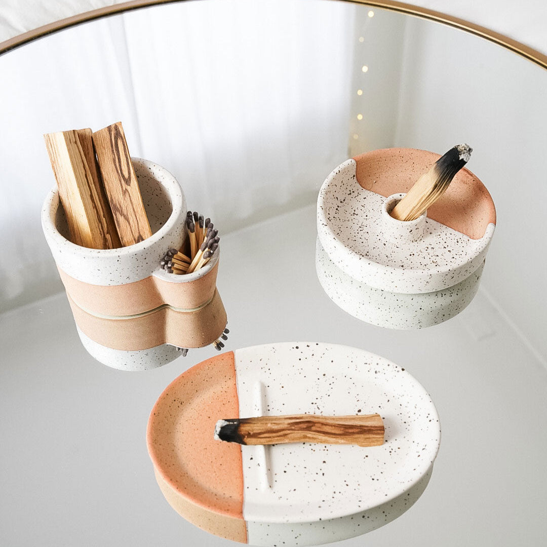 Set of ceramic dishes with wooden utensils on a white surface