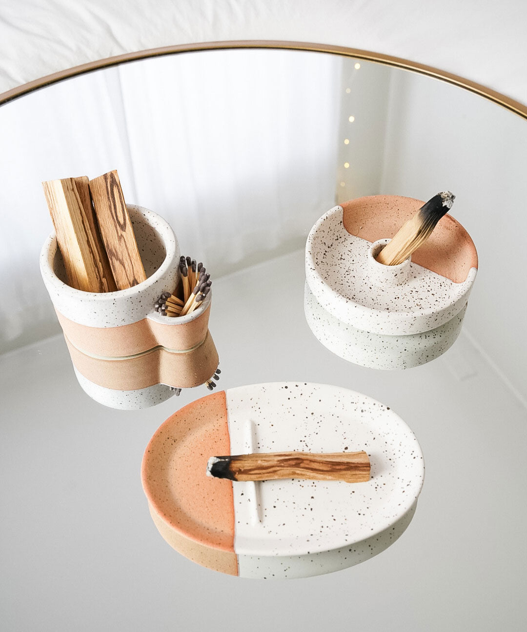 Set of ceramic dishes with wooden utensils on a white surface