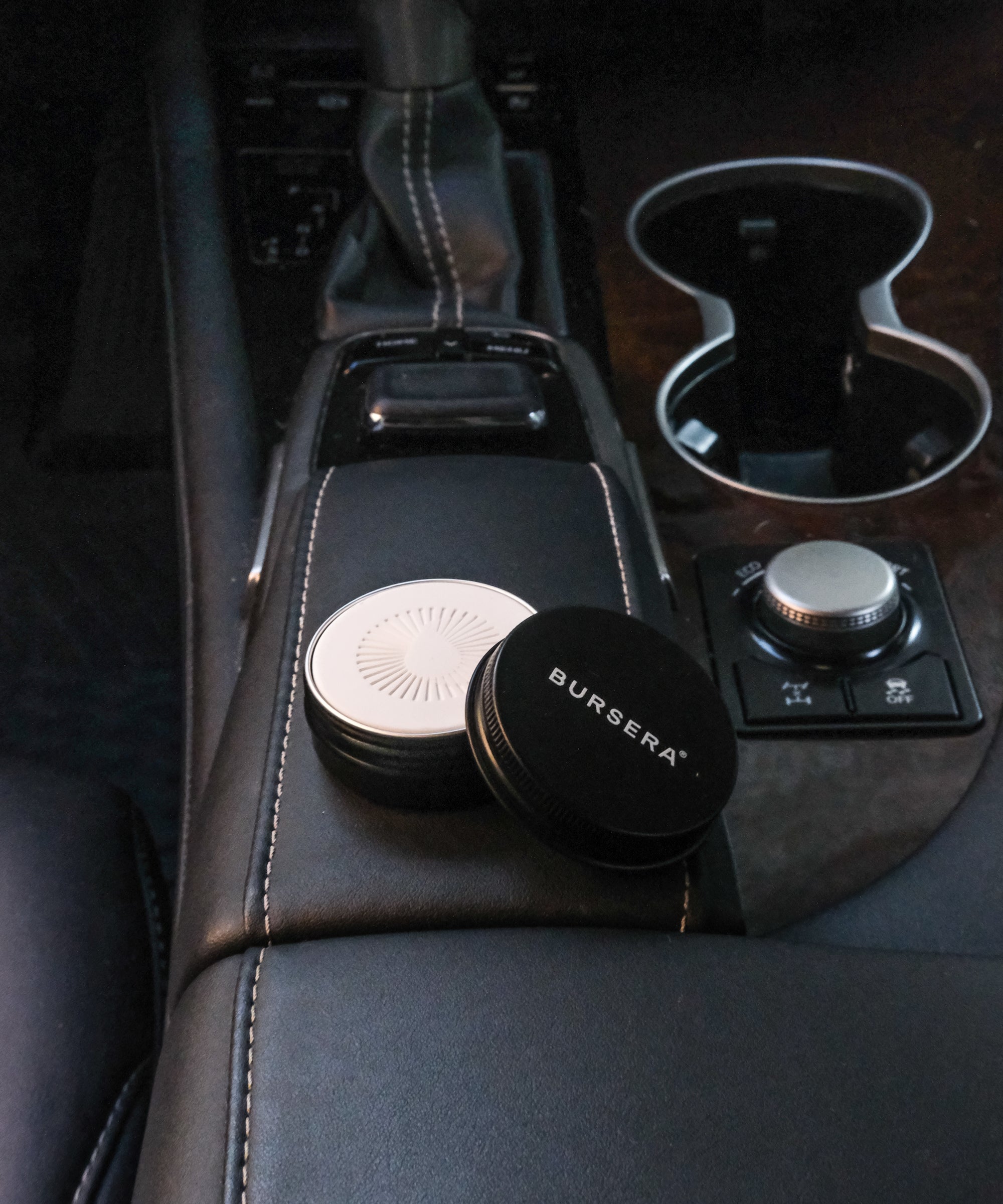 Burgsera car coasters on a car's center console with a cup holder in the background.
