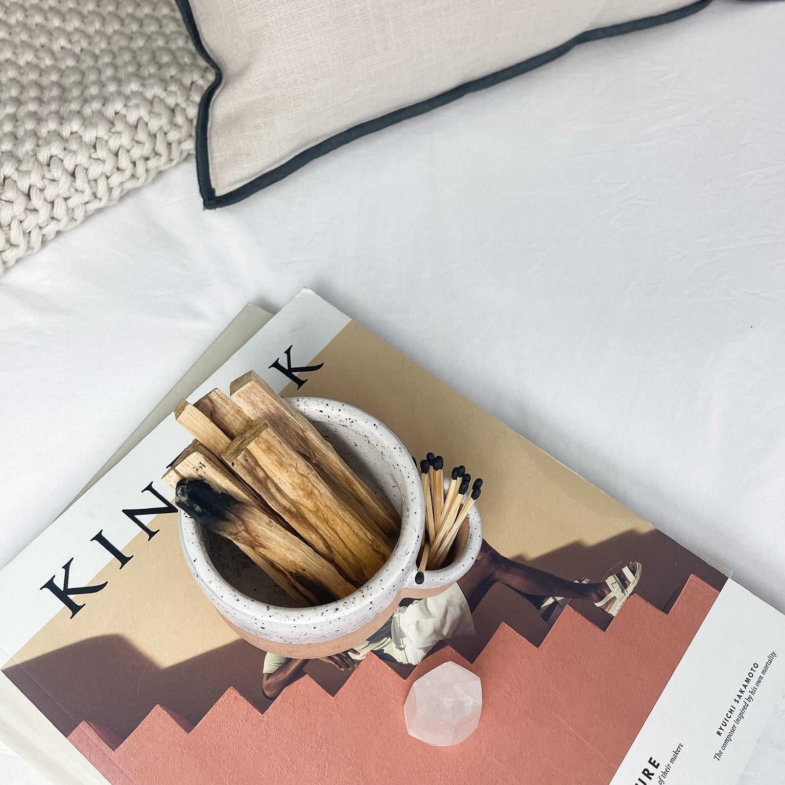 Small bowl with matches and wooden sticks on a magazine with a pillow in the background