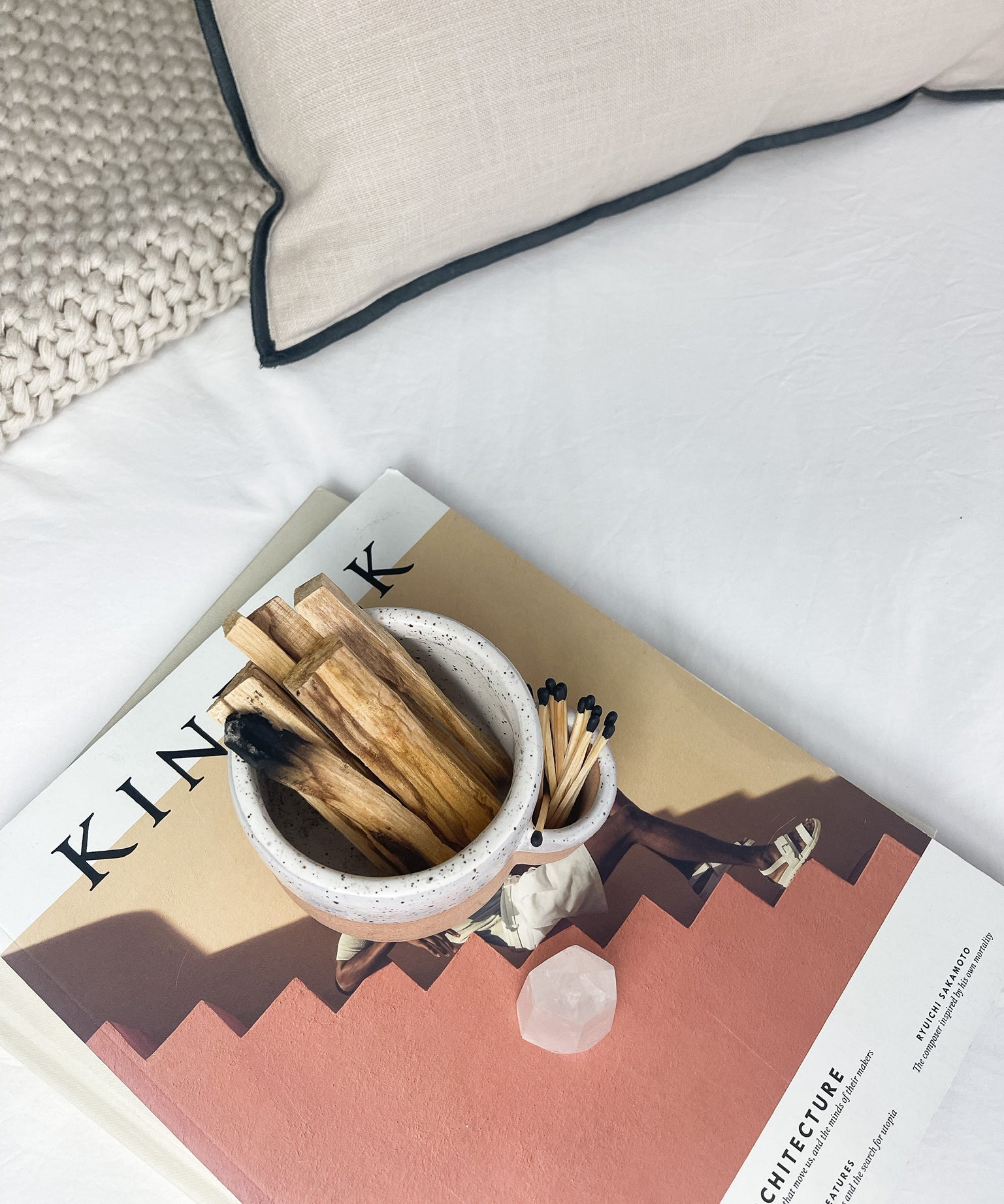 Small bowl with matches and wooden sticks on a magazine with a pillow in the background