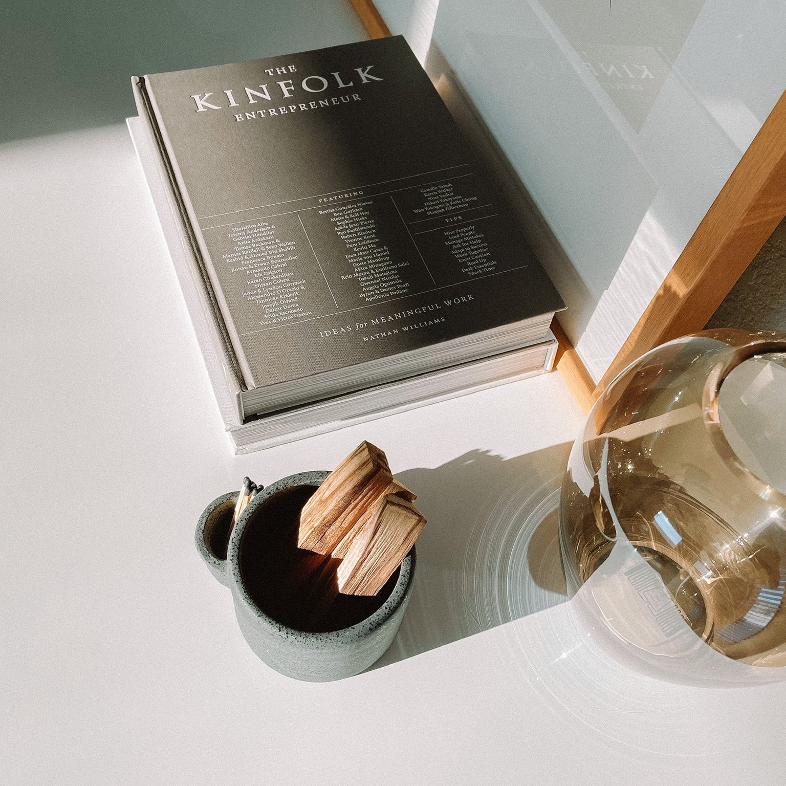 Book titled 'The Kinefolk Entrepreneur' on a surface with a mug and decorative item.