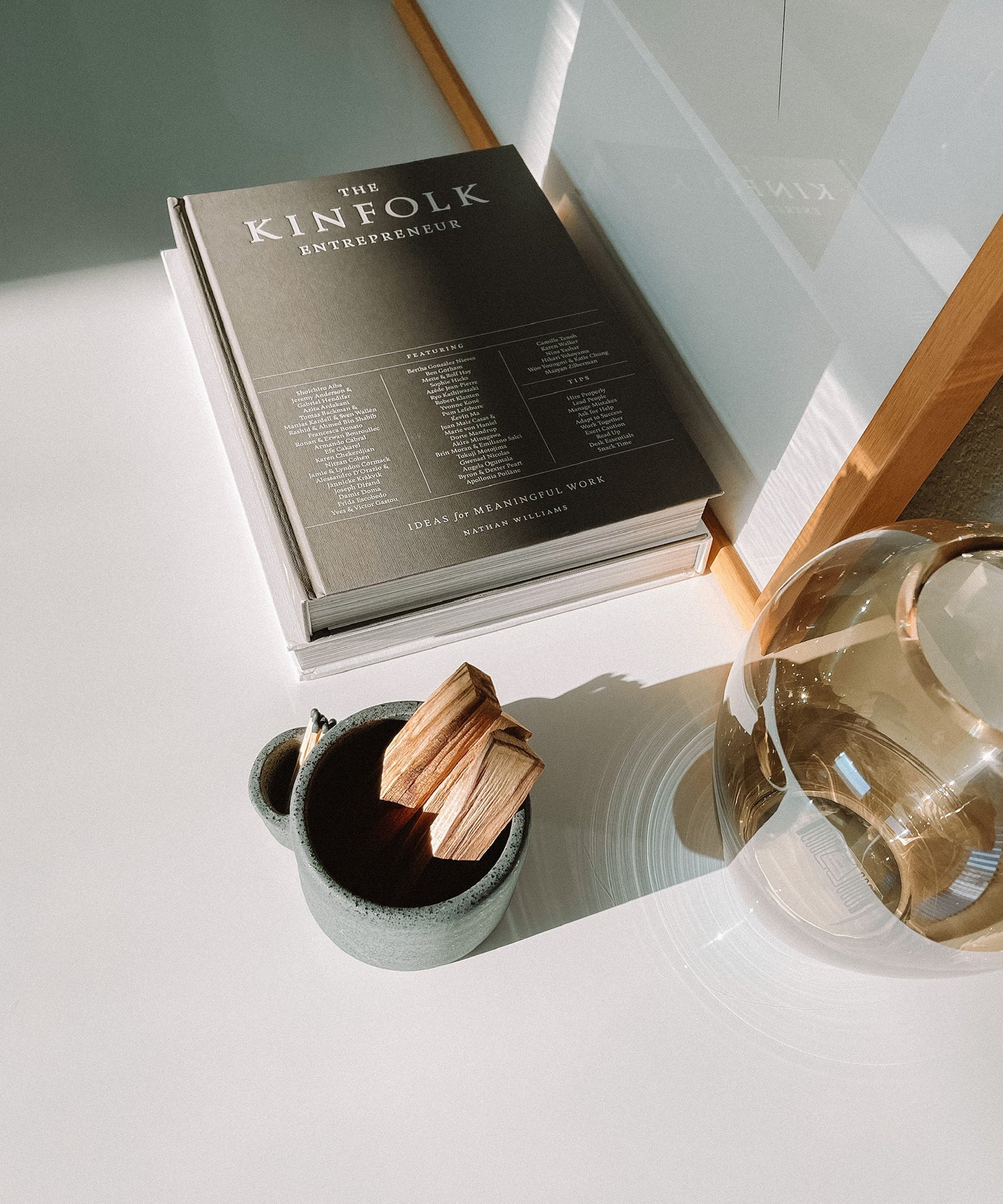 Book titled 'The Kinefolk Entrepreneur' on a surface with a mug and decorative item.