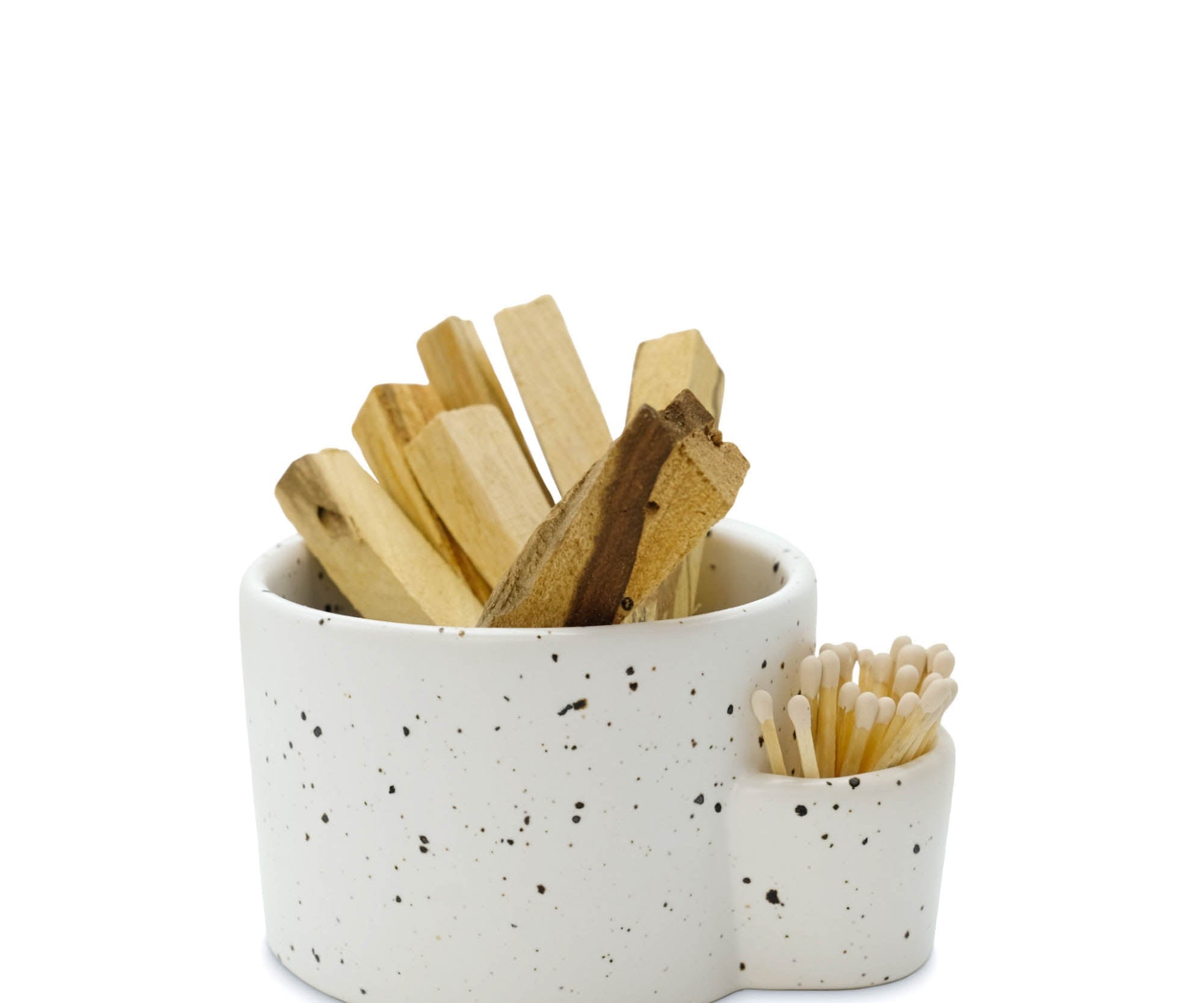 Speckled ceramic container with wooden sticks and a small bowl on a white background