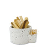 Speckled ceramic container with wooden sticks and a small bowl on a white background