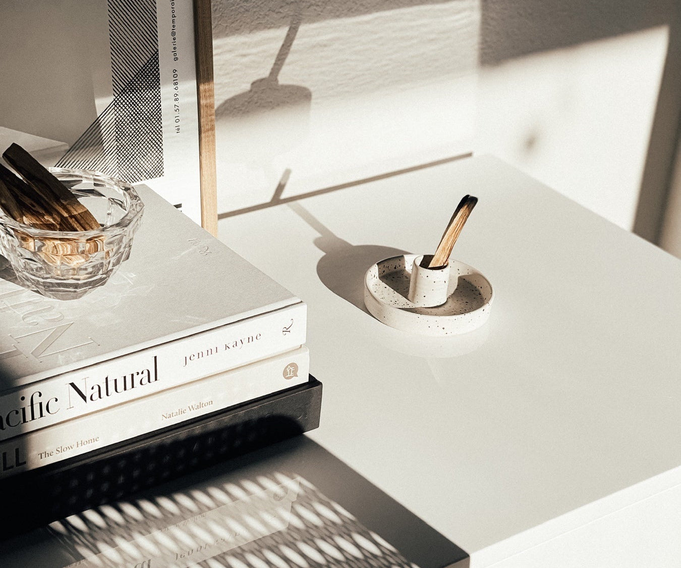 Modern nightstand with books, candle, and decorative items in a minimalistic setting