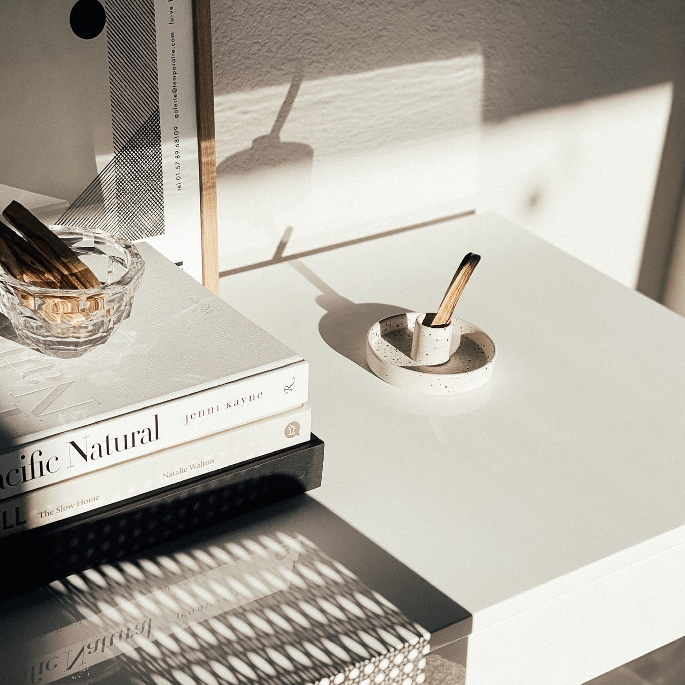 Modern nightstand with books, candle, and decorative items in a minimalistic setting