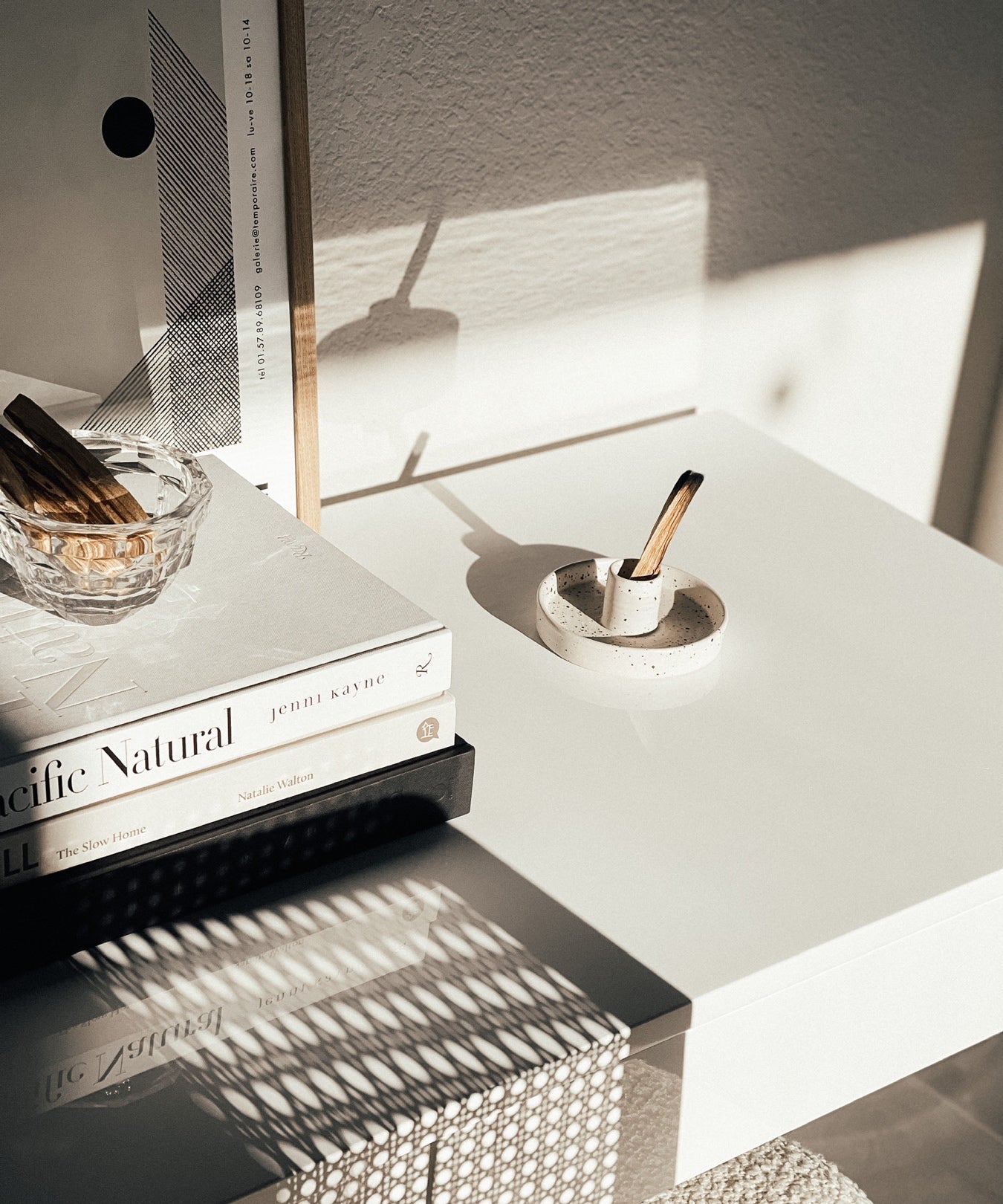 Modern nightstand with books, candle, and decorative items in a minimalistic setting