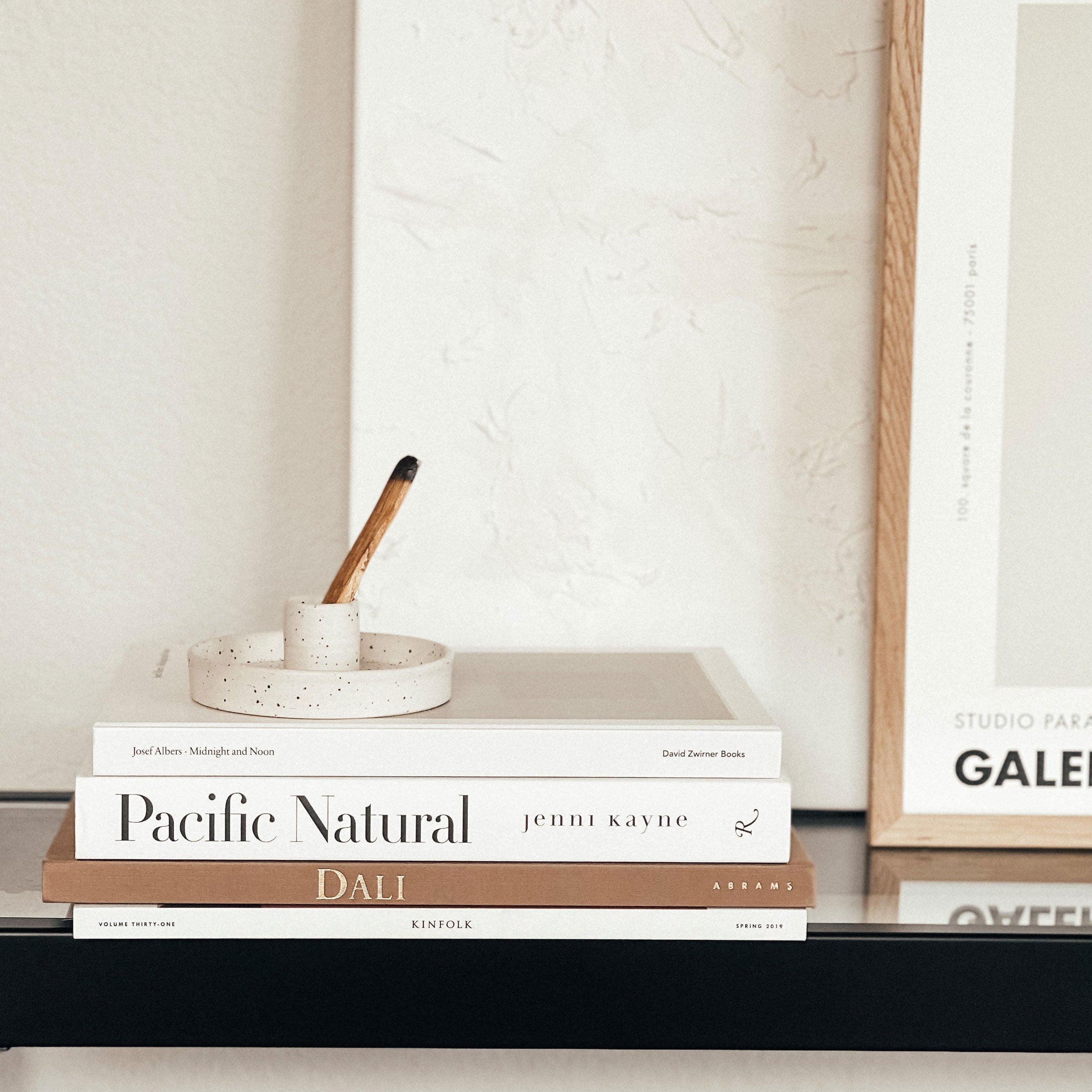 Stack of books on a shelf with a framed picture in the background