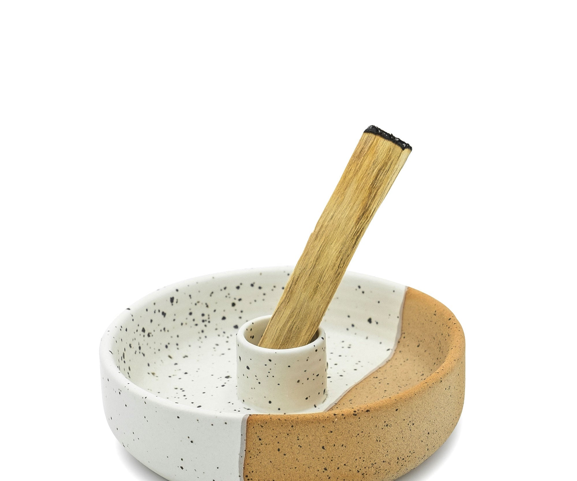 Ceramic bowl with speckled pattern and wooden spoon on a white background