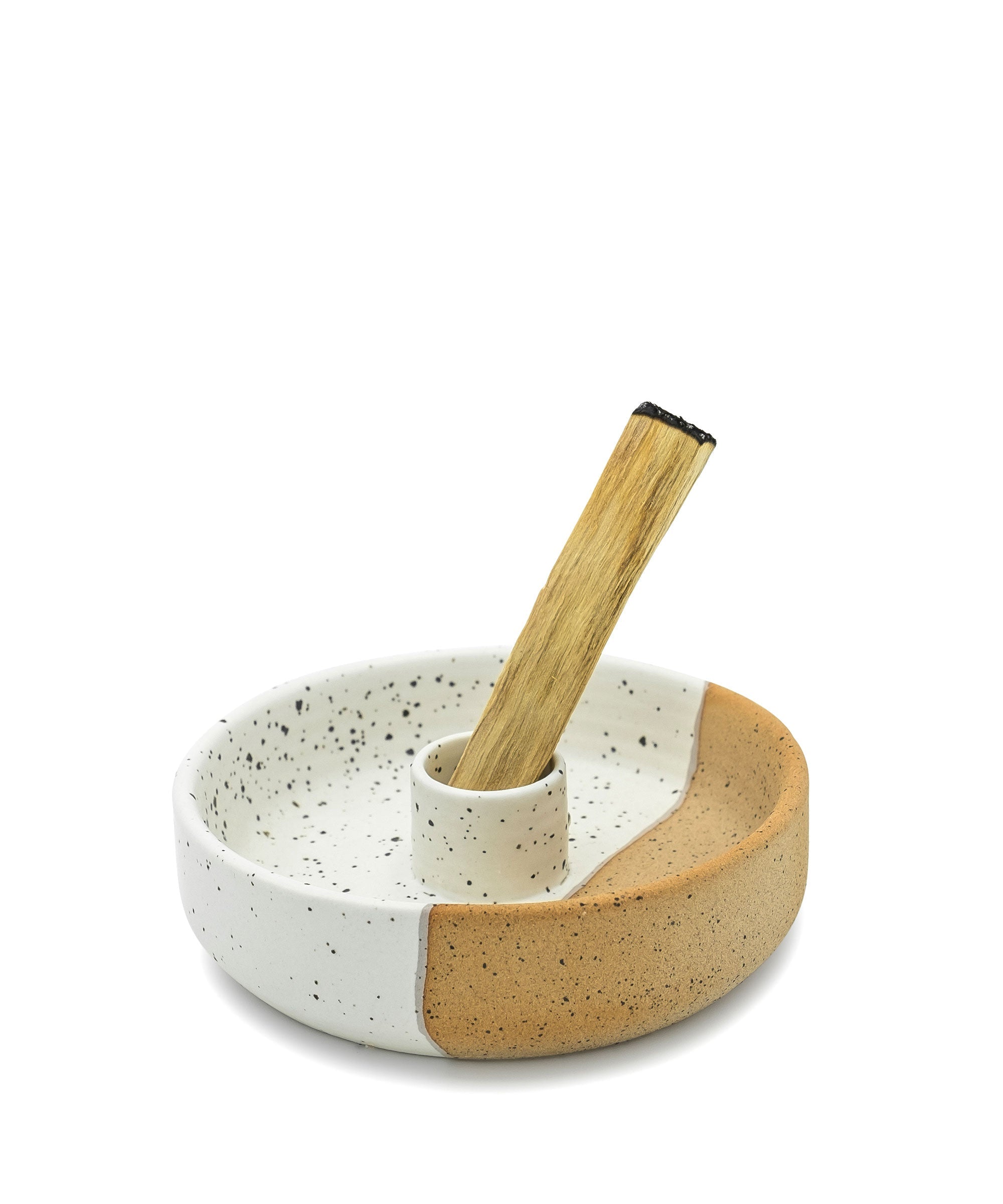 Ceramic bowl with speckled pattern and wooden spoon on a white background