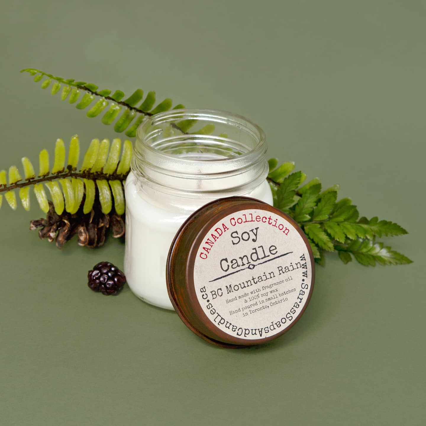 Soy candle in a glass jar with a wooden lid on a green background