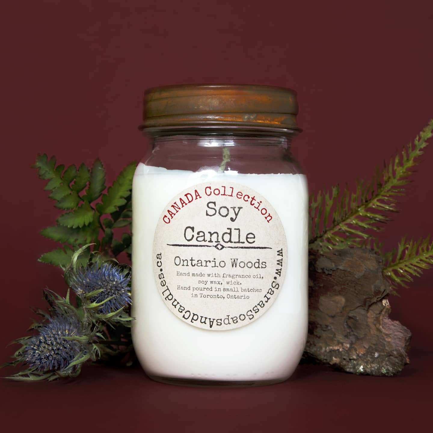 Soy candle in a mason jar with decorative elements on a red background