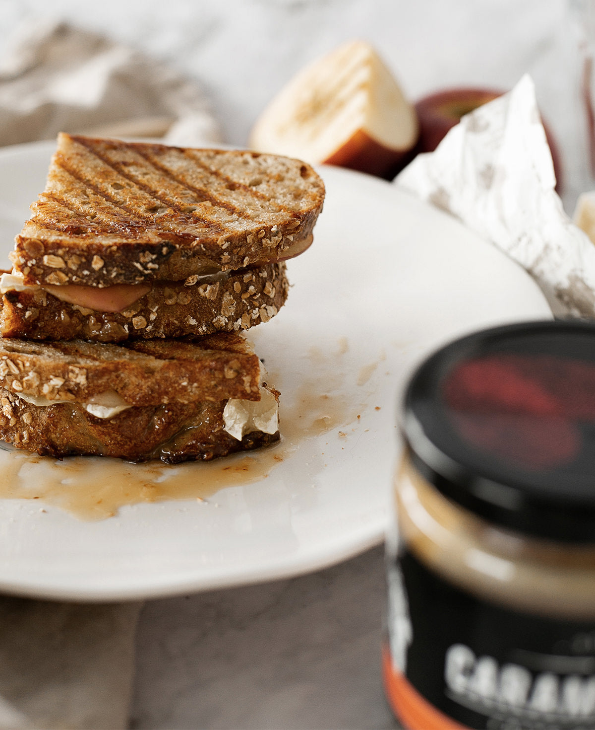 Stack of grilled sandwiches on a plate with a jar of caramel spread in the foreground.