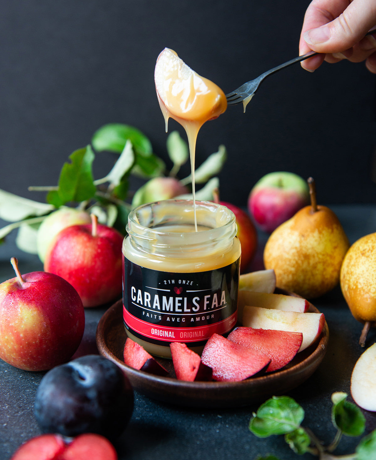 Caramels FAa jar with a spoonful of caramel over apples and pears on a dark background