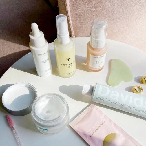 Cardea AuSet Collection of skincare and dental care products on a white surface with a soft pink background.