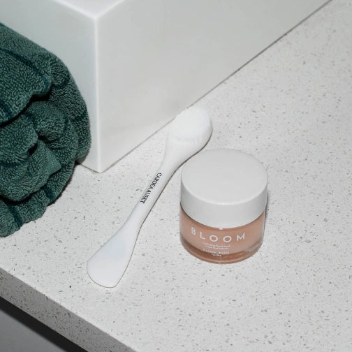 Cardea AuSet Bloom Jar on a bathroom counter with a green towel and white spatula.