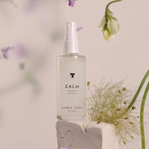 Bottle of 'Calm' product by Cardea AuSet with flowers in the background