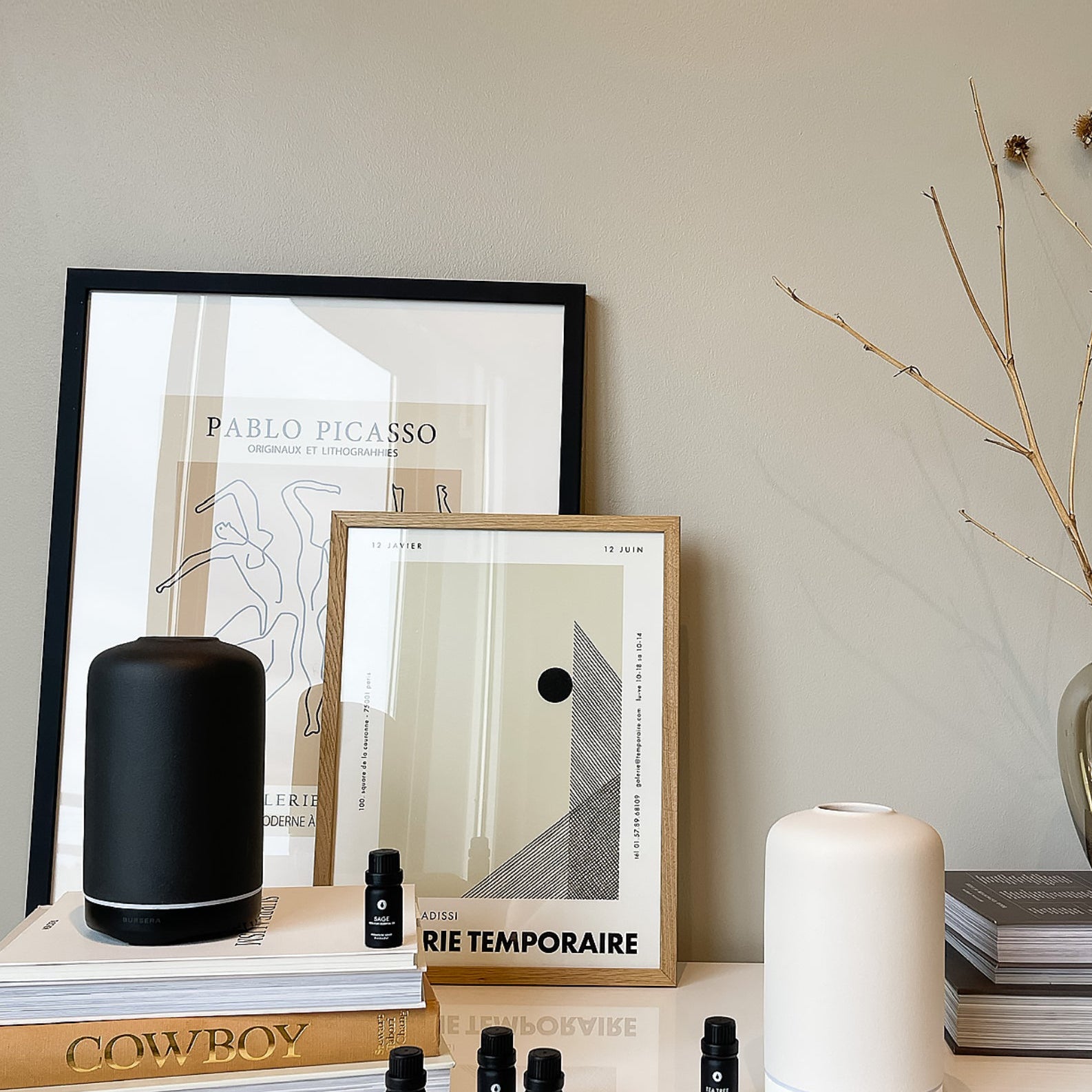 Decorative setup with framed art, books, and small bottles on a shelf.