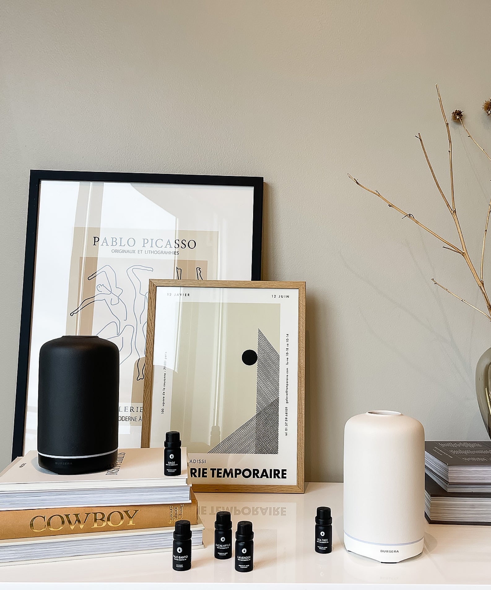 Decorative setup with framed art, books, and small bottles on a shelf.