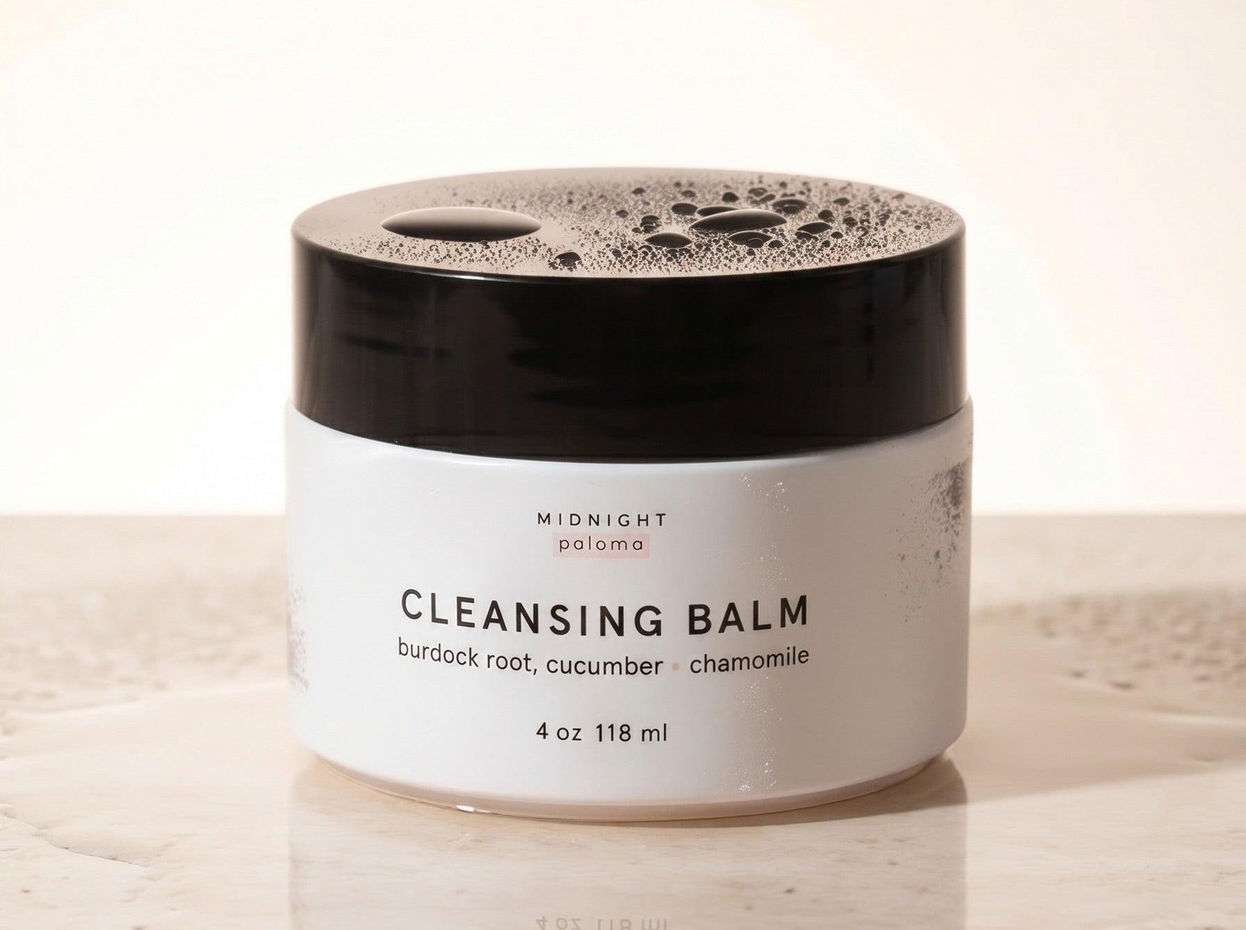 Cleansing balm jar with black lid on a light background