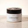 Cleansing balm jar with black lid on a light background