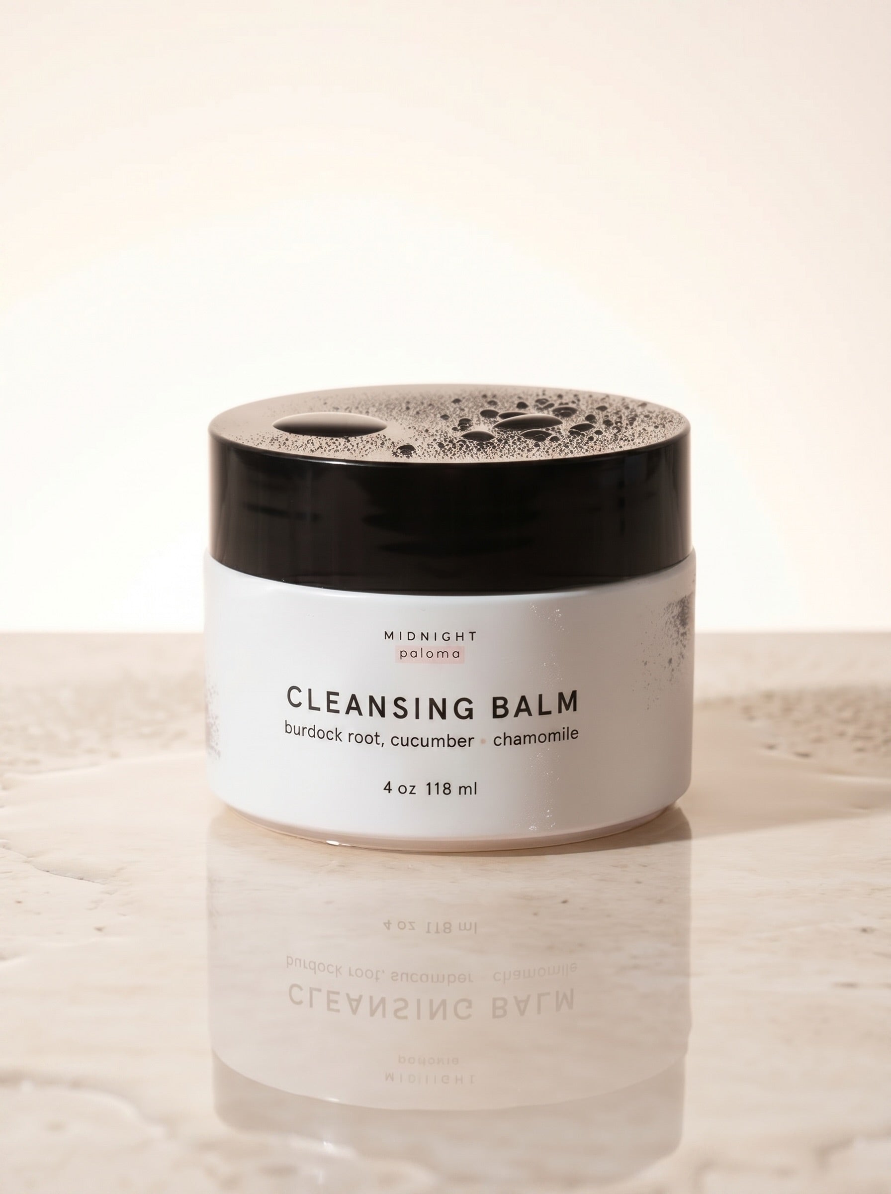 Cleansing balm jar with black lid on a light background