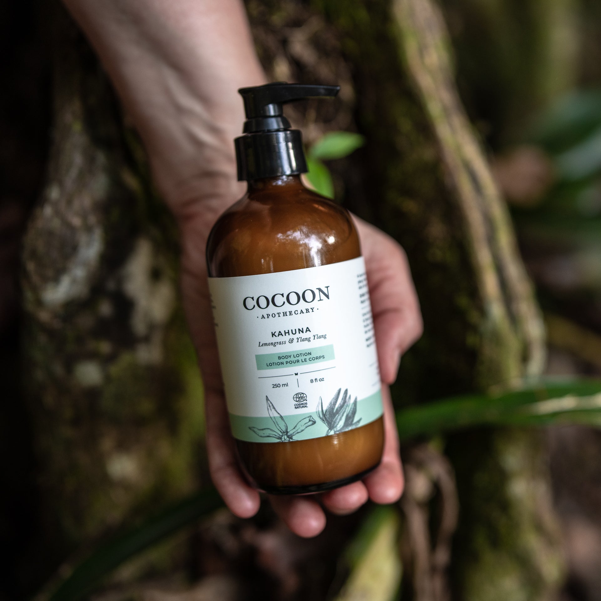 Hand holding a bottle of Cocoon Apothecary Kahuna soap against a natural background